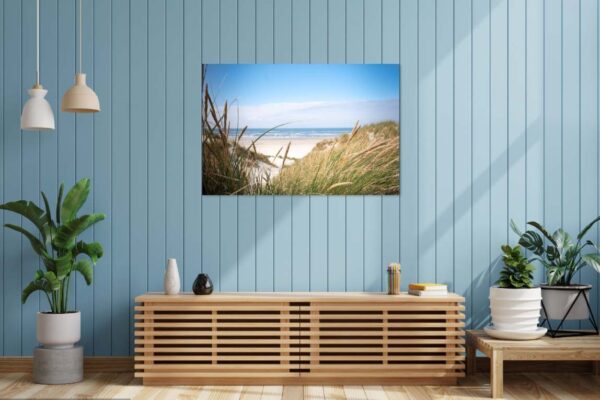 Modern interieur met planten en strandfoto aan muur.