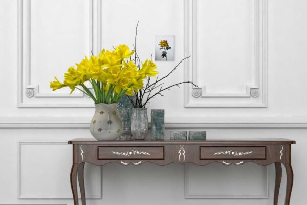 Vaas met gele narcissen op klassiek houten dressoir.
