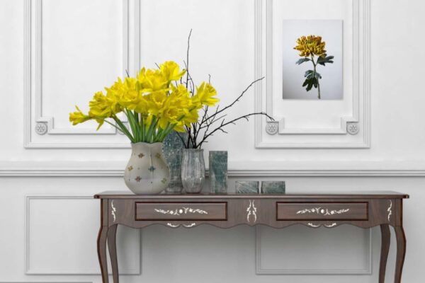 Vaas met gele narcissen op klassieke houten tafel.